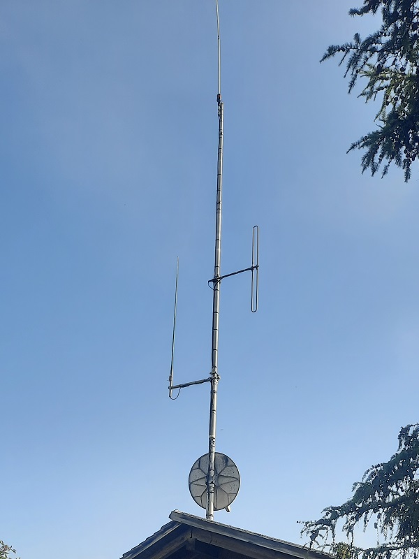 Antenna mast on the Hasenberg with vertical antennas and a satellite dish above a roof.